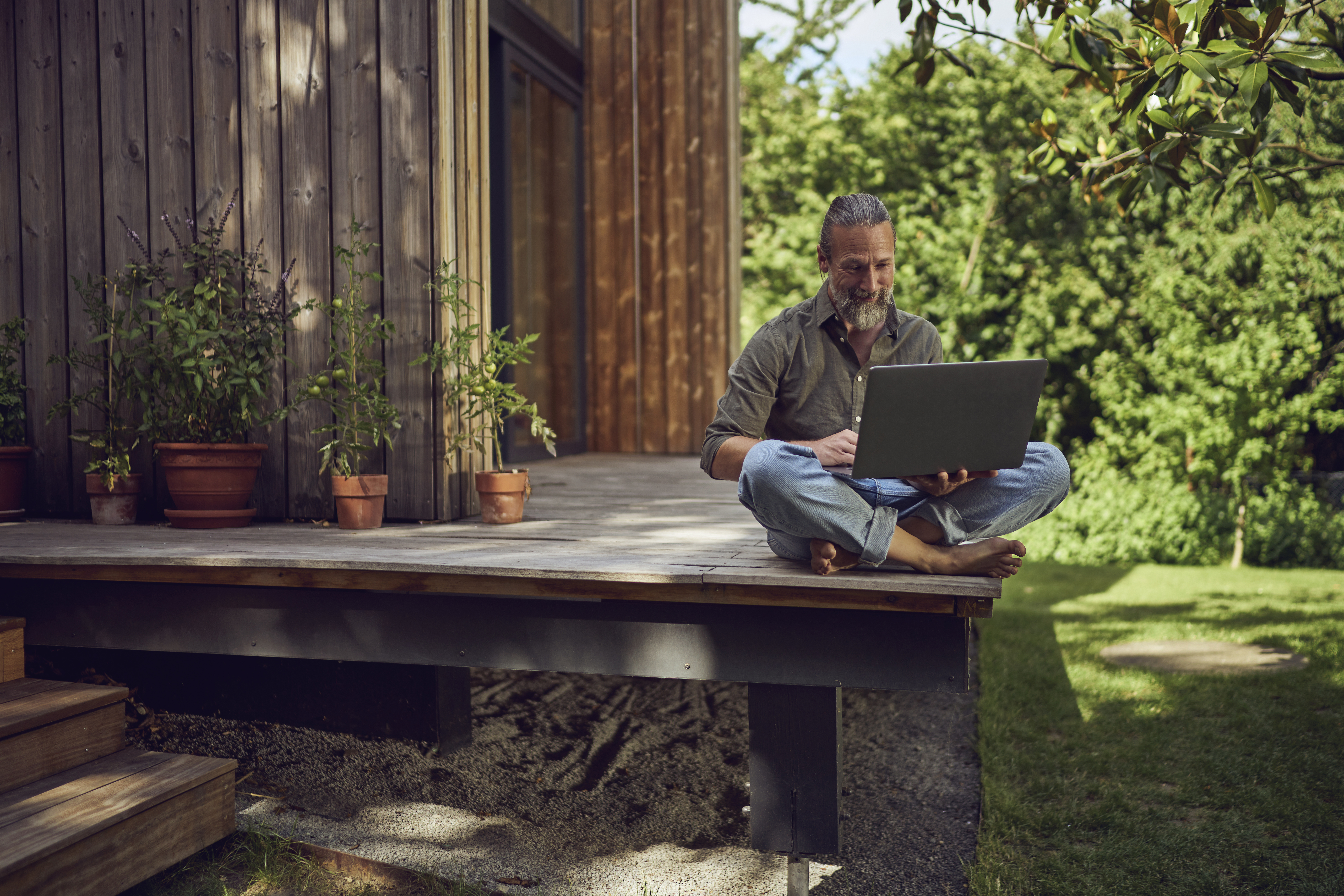 A person in a garden looking at a laptop
