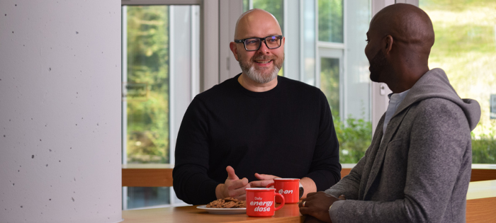 Two people stand chatting with E.ON branded coffee cups