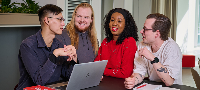 A group of people chatting together around a laptop