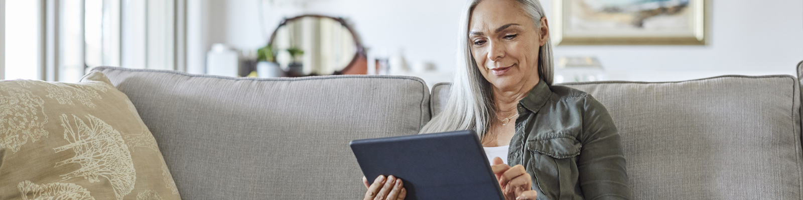 A woman sitting on a couch reading on her tablet